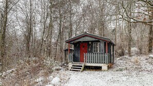 A small wooden cabin with a red door, surrounded by a snow-covered forest. - Beautiful home in Falkenberg with WiFi (Falkenberg)