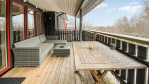 A covered outdoor seating area with a sofa and table, wooden deck flooring, and a view of the surrounding landscape. - Beautiful home in Falkenberg with WiFi (Falkenberg)