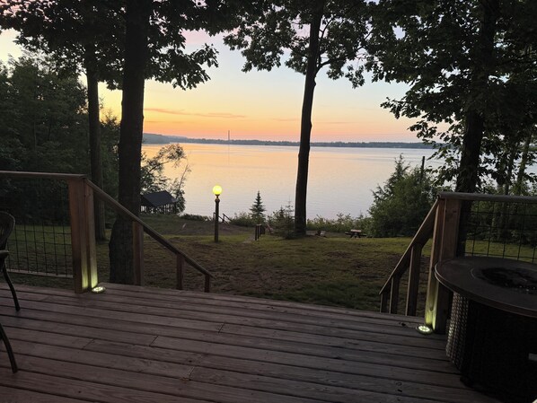 A wooden deck with a view of a lake at sunset.