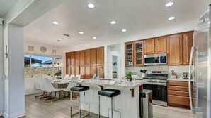 Una cocina moderna con armarios de madera, electrodomésticos de acero inoxidable y una isla central con taburetes de bar.