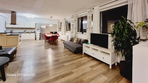 A modern living room with a dining area, kitchen, and large windows. - Apart Weinberg 1 - 8 persons vacation apartment (Gemeinde Imst)