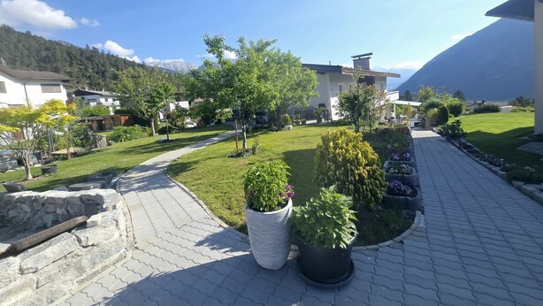 A residential area with paved pathways, potted plants, and houses with mountain views. - Apart Weinberg 1 - 8 persons vacation apartment (Gemeinde Imst)