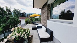 A modern outdoor patio with a seating area, a yellow umbrella, and a flower arrangement. - Apart Weinberg 1 - 8 persons vacation apartment (Gemeinde Imst)