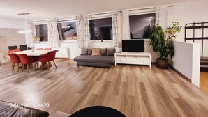 A modern living room with a dining area, a sofa, a TV, and a plant. - Apart Weinberg 1 - 8 persons vacation apartment (Gemeinde Imst)