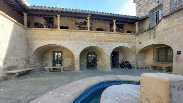 Un cortile con piscina, panchine e una motocicletta.
