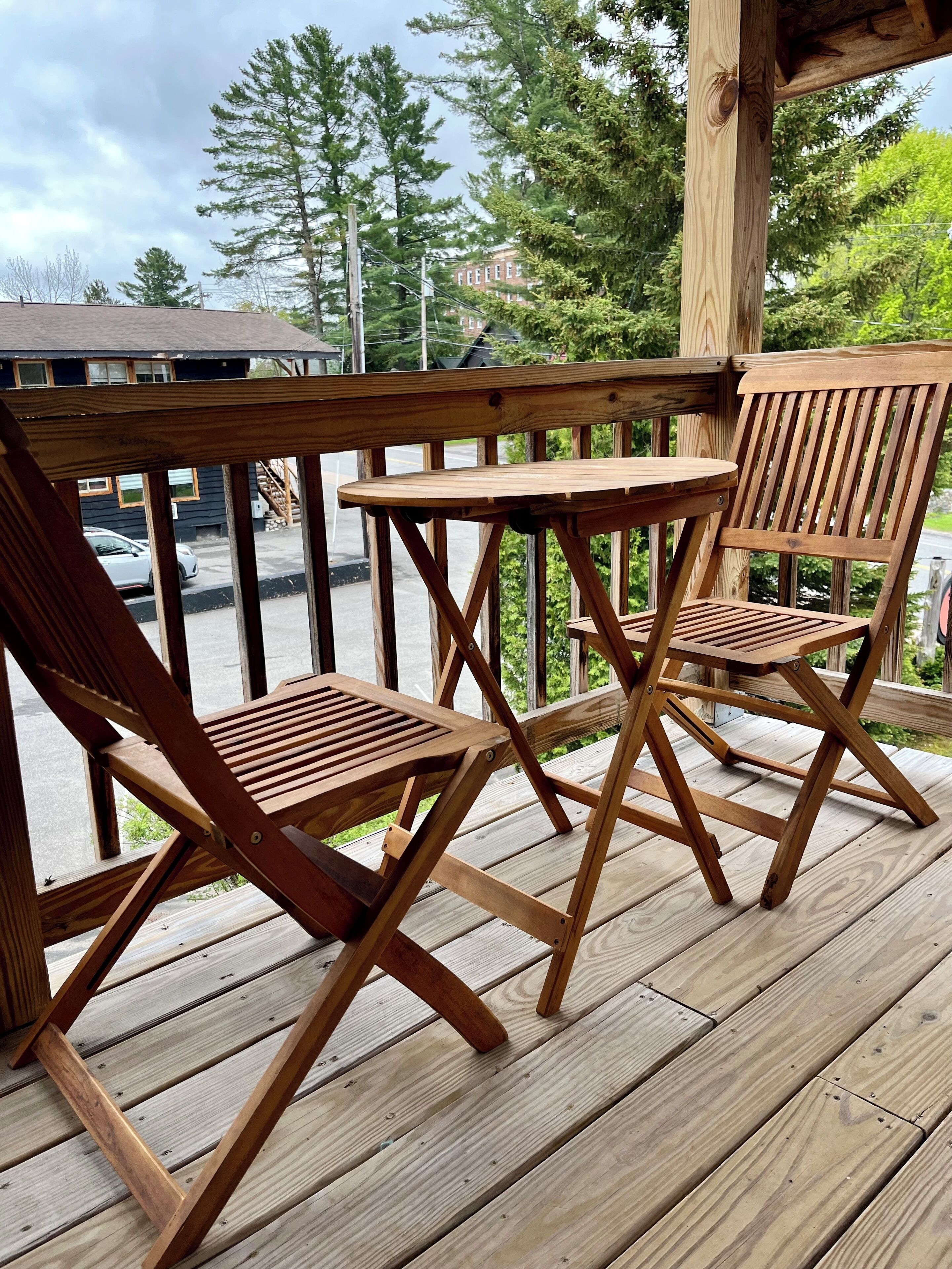 A wooden deck with two lounge chairs and a small table.