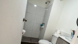 Un baño pequeño con inodoro, lavamanos y ducha.