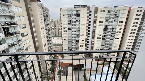 Un edificio residencial de gran altura con varios balcones, un patio interior y una piscina.