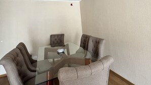 Un comedor con una mesa de vidrio y cuatro sillas tapizadas.
