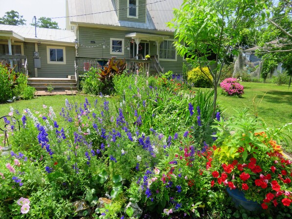A house with a front porch, a garden with various flowers, and a lawn.