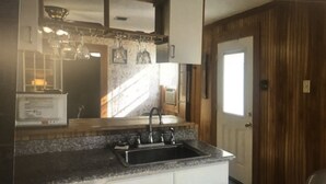 Una cocina con encimera de granito, pileta de acero inoxidable y muebles color blanco.