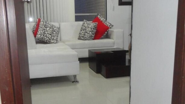 A living room with a white sofa, two patterned throw pillows, and a dark coffee table. - Emdoralahouse (Cali)