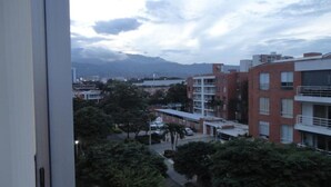 A residential area with multi-story buildings, some with balconies, and a mountainous backdrop. - Emdoralahouse (Cali)