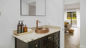A bathroom with a marble countertop, a copper vessel sink, dark cabinets, and a large mirror. - [lounge like locals] walk to siesta beach +bikes (Siesta Key)