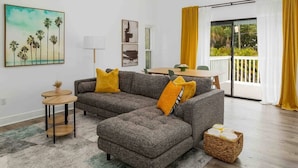 A modern living room with a grey sectional sofa, yellow cushions, a small round table, and a wicker basket. - [lounge like locals] walk to siesta beach +bikes (Siesta Key)