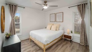 A bedroom with a bed, bedside tables, a ceiling fan, and curtains. - [lounge like locals] walk to siesta beach +bikes (Siesta Key)