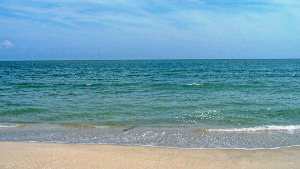 Una playa con mar tranquilo y cielo despejado.