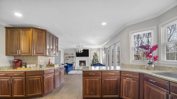 A spacious kitchen with wooden cabinets, a granite countertop, and a built-in fireplace.