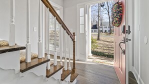 A staircase with white railings and wooden steps leading to a door with a wreath.