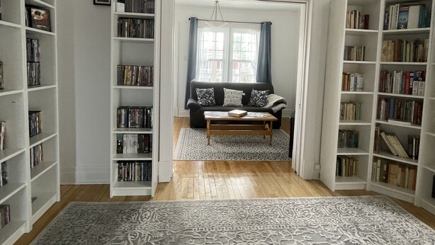 Un salón espacioso con sofá, mesa de centro y estanterías llenas de libros.