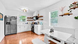 Una cucina moderna con mobili bianchi, elettrodomestici in acciaio inossidabile e pavimento in legno.