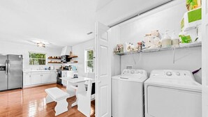 Una cucina moderna con mobili bianchi, frigorifero in acciaio inossidabile, forno integrato e lavatrice.