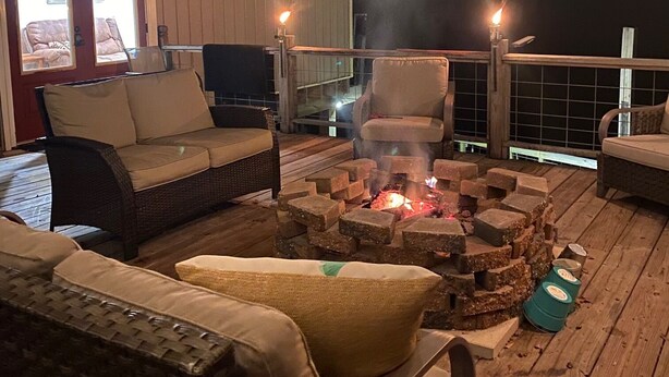 Un'area relax all'aperto con mobili in vimini, un braciere e vista sul cielo notturno.