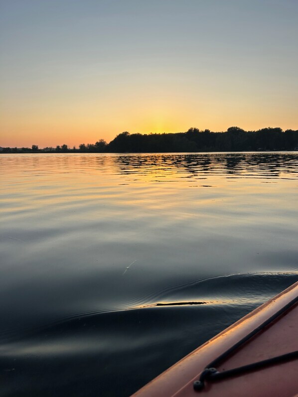 A calm lake at sunset with a boat in the foreground.