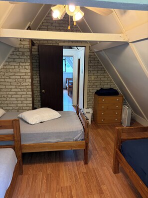 A small, cozy attic bedroom with a wooden bed, a dresser, and a radiator. - 3 bedroom 2 bath renovated A frame on channel to Kuhn lake and the Barbee Chain (Pierceton)