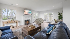 A modern living room with a fireplace, a large sofa, a coffee table, and a television.