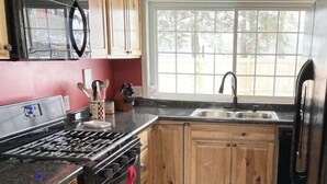 Une cuisine avec des meubles en bois, un poêle noir et un réfrigérateur en acier inoxydable.