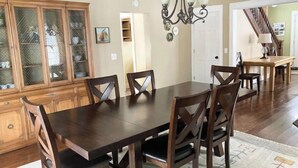 Un coin repas avec une table et des chaises en bois foncé, un lustre et un buffet en bois doté de portes en verre.