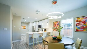 Une cuisine moderne avec des meubles blancs, un îlot central et des luminaires suspendus.