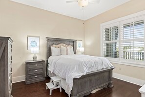 A bedroom with a large bed, a nightstand, a dresser, and a window with blinds. - Redfish Village - Beach Please - 2BR/2BA - Gulf Views - Seasonal Beach Tram (Santa Rosa Beach)