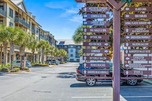 A street view with a signpost listing various local businesses and services.