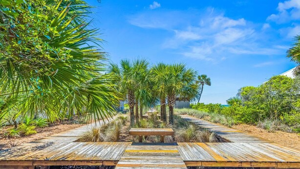 A wooden boardwalk leading to a central area with benches and palm trees. - Redfish Village - Beach Please - 2BR/2BA - Gulf Views - Seasonal Beach Tram (Santa Rosa Beach)