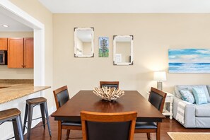 A dining area with a wooden table and chairs, a decorative centerpiece, and a painting on the wall.