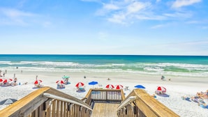 A wooden boardwalk leading to a beach with umbrellas and people. - Redfish Village - Beach Please - 2BR/2BA - Gulf Views - Seasonal Beach Tram (Santa Rosa Beach)