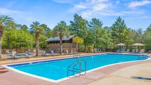 A swimming pool with lounge chairs and umbrellas, surrounded by trees and a wooden building. - Redfish Village - Beach Please - 2BR/2BA - Gulf Views - Seasonal Beach Tram (Santa Rosa Beach)