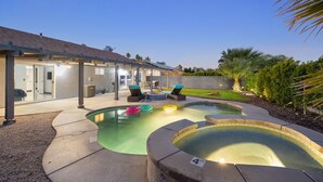 Un jardin avec une piscine, des chaises longues et un patio couvert.