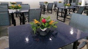 A conference room with multiple tables and chairs, some with potted plants. - Island Hopper Hotel (Kosrae)