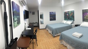 A hotel room with two beds, a desk, a chair, and artwork on the walls. - Island Hopper Hotel (Kosrae)