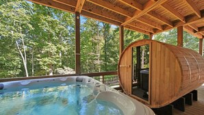 A hot tub with a wooden barrel sauna, surrounded by a wooden deck and trees. - Outdoor Barrel Sauna, Hot Tub, Fire Pit, 2 Full Kitchens, (Morganton)