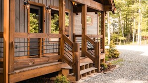 A wooden cabin with a porch, steps, and a gravel driveway. - Outdoor Barrel Sauna, Hot Tub, Fire Pit, 2 Full Kitchens, (Morganton)