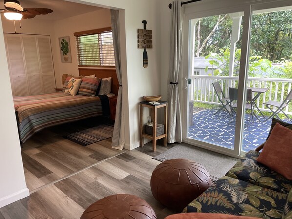 A cozy bedroom with a bed, a small table, and a view of a balcony.