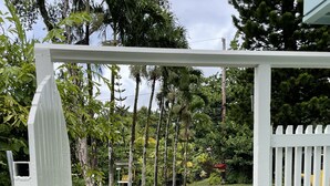 A white wooden gate leading to a grassy area with a stone pathway and trees. - Kaloli Point retreat 3 blocks from the ocean and minutes to Shipman Beach trail! (Keaau)
