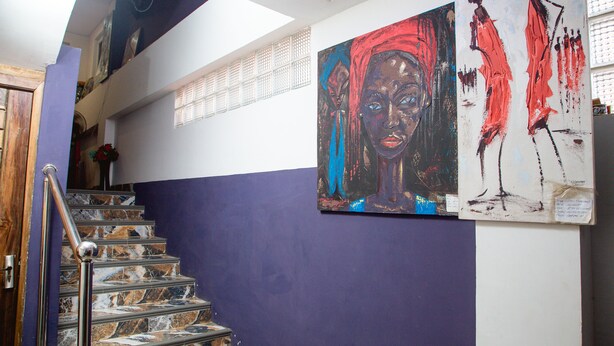 A staircase with marble steps and a metal handrail, leading to a room with a purple wall and two large abstract paintings. - Ark Hotel and Apartments (Accra)