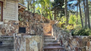 Una escalera de piedra que lleva a un edificio de madera con un muro de piedra con la inscripción "7 Sunset".