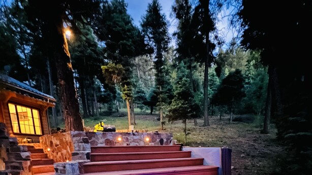 Una terraza de madera con un jacuzzi, escalones de piedra y un muro de piedra.