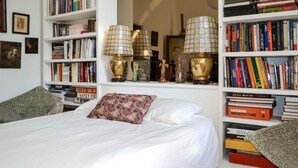 A bedroom with a large bed, two bedside tables, and a bookshelf filled with books. - Beautiful home in Léognan with sauna (Léognan)